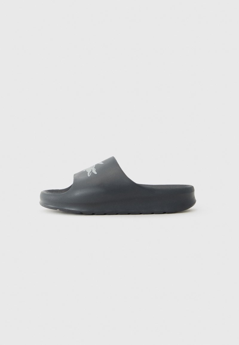 Grå slip-on sandal tillverkad av slät gummi. Har en bred rem och en texturerad sula. En subtil grafisk design finns på ovansidan.