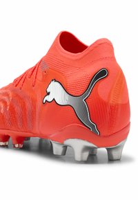 Punainen jalkapallokengän ja sukka-tyylisen varren yhdistelmä, teksturoitu päällinen, näkyvä Puma-logo mustavalkoisena ja hopeiset nastat ulkopohjassa.