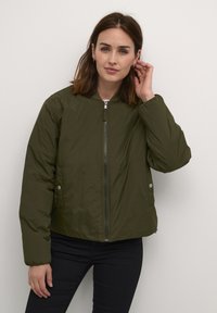 Oliivroheline lühike bomber-jakk, millel on lukuga eesmine osa, külgsed nööbid ja sile tekstuur. Pikkade varrukatega ja ümar kaelus täiustavad disaini.