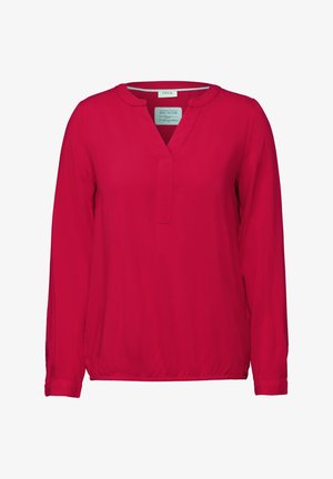 Röd blus med långa ärmar, V-ringning och subtil struktur. Har rakt avslut och elastisk midja. Etikett visar varumärket "CECIIL".
