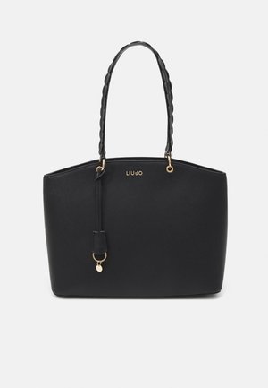 Zwarte leren tas met gedraaide handvatten, gouden beslag en een klein hangend hangertje, met een minimalistisch ontwerp en merklogo.