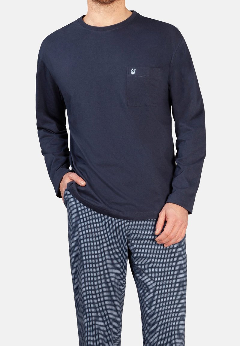 Marineblaues langärmeliges Baumwoll-T-Shirt mit einer Brusttasche und kleinem Logo. Ergänzt durch gemusterte, locker geschnittene Hosen in hellblauen Tönen.