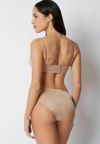 Beige bh en set met hoge taille slip, gemaakt van gladde stof. Verstelbare banden en haaksluiting op de rug. Eenvoudig, naadloos ontwerp.