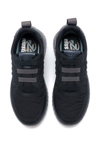 Un par de zapatillas deportivas negras con correas elásticas grises, suelas gruesas y tiradores, vistas desde arriba sobre un fondo blanco.