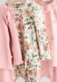 Drei Babybekleidungsstücke sind ausgestellt: zwei rosa Artikel und ein weißes mit Blumenmuster. Zu den Merkmalen gehören RüschenschSleeves und ein Blumendesign mit grünen Akzenten.