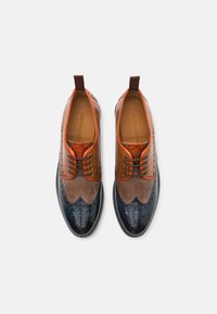 Brown and blue leather shoes with brogue detailing, featuring an orange accent on the upper and a rounded toe design.