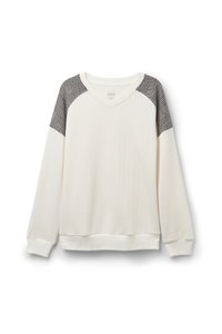 Vit ribbad sweatshirt med axeldetaljer i svart och vitt rutig mönster samt V-ringning. Har långa ärmar och en åtsittande nederkant.