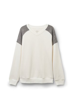 Vit ribbad sweatshirt med axeldetaljer i svart och vitt rutig mönster samt V-ringning. Har långa ärmar och en åtsittande nederkant.
