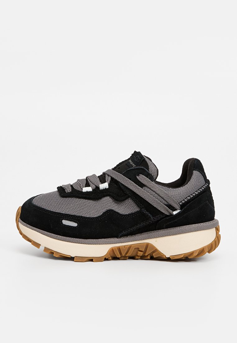 Zwarte en grijze sport sneaker met dikke beige zool en bruine loopvlak, voorzien van grijze veters en gemaakt van suede en mesh materiaal.