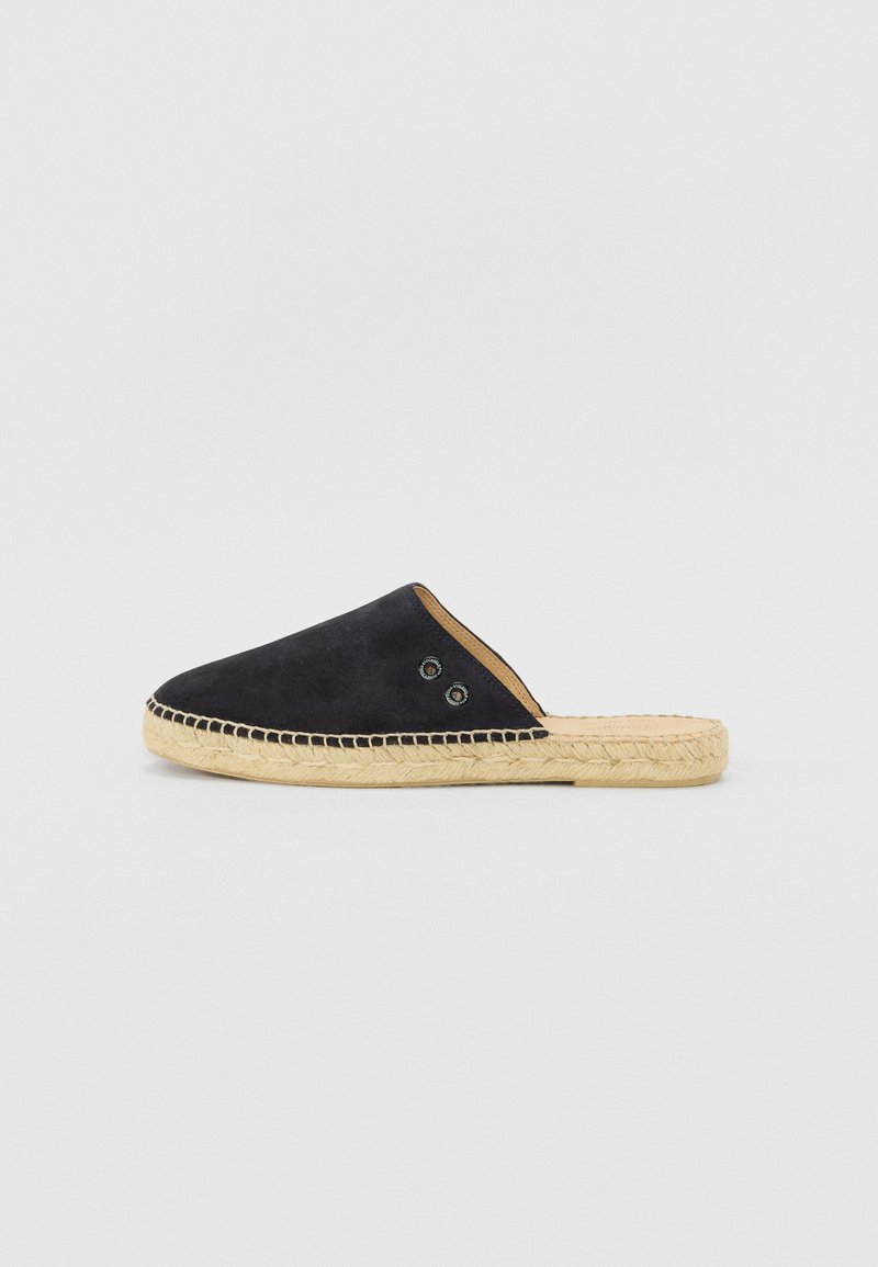 Navy suede slip-on shoe with a woven jute sole. Features two decorative eyelets on the upper side. Smooth texture with a rounded shape.