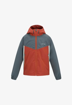 Glimlachende jongen loopt, draagt een rood-grijs gevoerde jas met capuchon, een beige overhemd, grijze korte broek, zwarte sokken, zwarte schoenen en een groene pet.