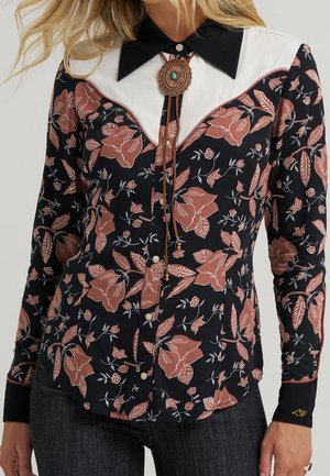 Czarna koszula z różowymi kwiatowymi wzorami, kontrastującym białym karczkiem, czarnym kołnierzem, perłowymi zatrzaskami i krawatem bolo z turkusowym środkiem.