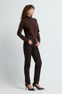 Brun polotröja kombinerad med mörkbruna figursydda byxor och mörka klackskor, med en slät textur och skräddarsydd design.