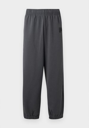 Pantaloni jogger elasticizzati di colore grigio scuro con vita e caviglie elastiche, con un piccolo logo testurizzato sulla parte superiore della coscia sinistra, su uno sfondo semplice.