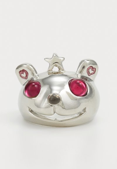 Silberfarbene Ring in Form eines Bärenkopfes mit pinken Edelsteinen als Augen, einem Stern-Akkzent oben und herzförmigen Details an den Ohren. Glatte, glänzende Oberflächenbeschaffenheit.