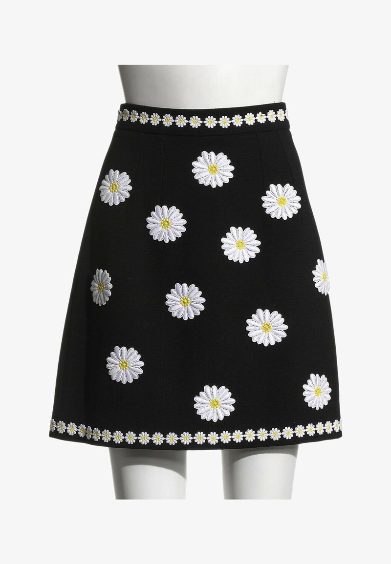 Jupe noire trapèze avec des marguerites blanches brodées aux centres jaunes, comportant une bordure de marguerites à la taille et à l'ourlet.