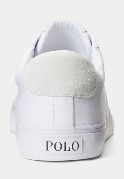 Biały sneaker widziany od tyłu z zamszową łatą na pięcie i etykietą "POLO" na podeszwie.