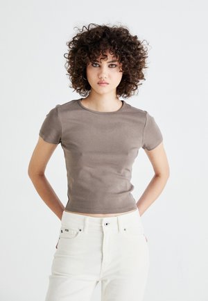 Brown fitted shirt with a round neckline and short sleeves, paired with high-waisted white corduroy pants. Smooth texture, simple design.