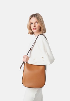 Tan leather shoulder bag with a smooth texture, structured shape, and a dark brown adjustable strap, featuring minimal branding detail.
