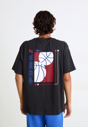 Czarny bawełniany T-shirt z graficznym wzorem dwóch piłek do koszykówki oraz czerwono-niebieskimi paskami na plecach. Luźny krój z krótkimi rękawami.