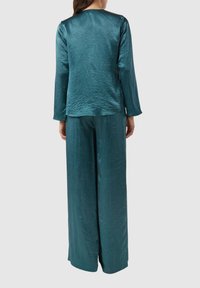 Set aus einem langen Oberteil mit langen Ärmeln und weit geschnittenen Hosen aus Satin in Türkis, mit glatter Textur und lockerem Sitz, dezent schimmernd und mit knitterartigem Muster.