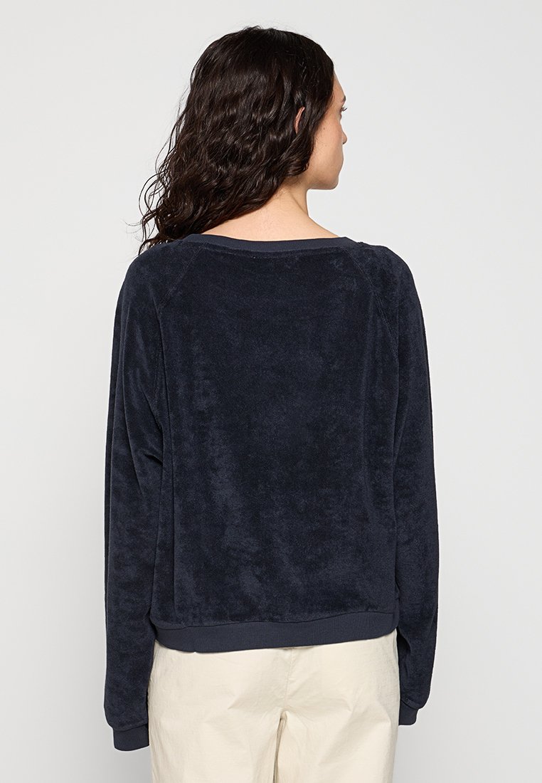 Marineblauer Fleece-Pullover mit weicher Textur, langen Raglanärmeln und rundem Halsausschnitt. Mit elastischem Saum und Bündchen.