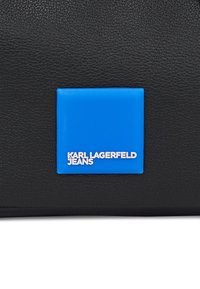 Čierny textúrovaný materiálový vak s námestovým modrým nášivkom, na ktorom je výrazne zobrazený biely text "KARL LAGERFELD JEANS".
