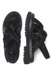 Zwarte leren sandalen met kruislings gespen, dikke rubberen zool met een gestructureerde loopvlak en een rits om de enkel voor een veilige pasvorm.