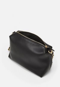 Borsa in pelle nera con zip dorata parzialmente aperta e tracolla in catena dorata su uno sfondo bianco.