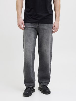 Vervaagde zwarte jeans met een relaxte pasvorm, voorzien van voorzakken en riemlussen, gecombineerd met zwarte veterschoenen en een zwart t-shirt.
