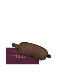 Maschera per dormire in seta marrone di lusso con cinturino elastico appoggiata su una scatola viola etichettata "le silque Pure Moments."