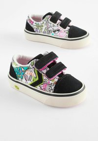Sorte og hvide sneakers med graffiti-inspirerede mønstre, velcro-stropper, polstret pink foring og en struktureret gummisål, der har en smiley-detajle.