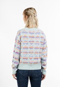 Pastellblau gestrickter Pullover mit einem mehrfarbigen abstrakten Muster, rundem Ausschnitt und gerippten Bündchen und Saum. Getragen mit dunklen Jeans.