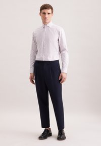 Camicia a maniche lunghe a righe bianche e rosa chiaro, abbinata a pantaloni blu navy. Scarpe nere stringate completano il look. Design semplice e vestibilità sartoriale.