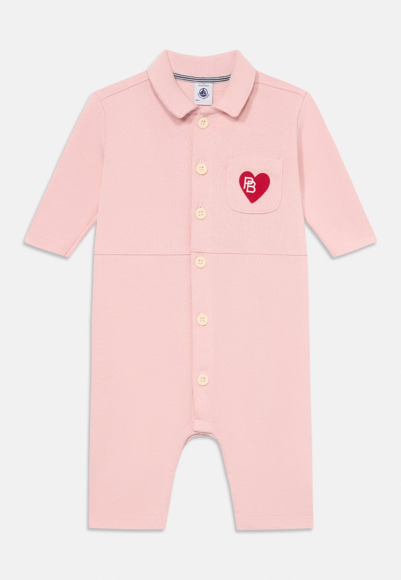 Jasnoróżowy kombinezon z krótkim rękawem, z kołnierzykiem, zapinany na guziki, z kieszonką na piersi, na której znajduje się czerwone serce i inicjały. Miękka tekstura materiału.
