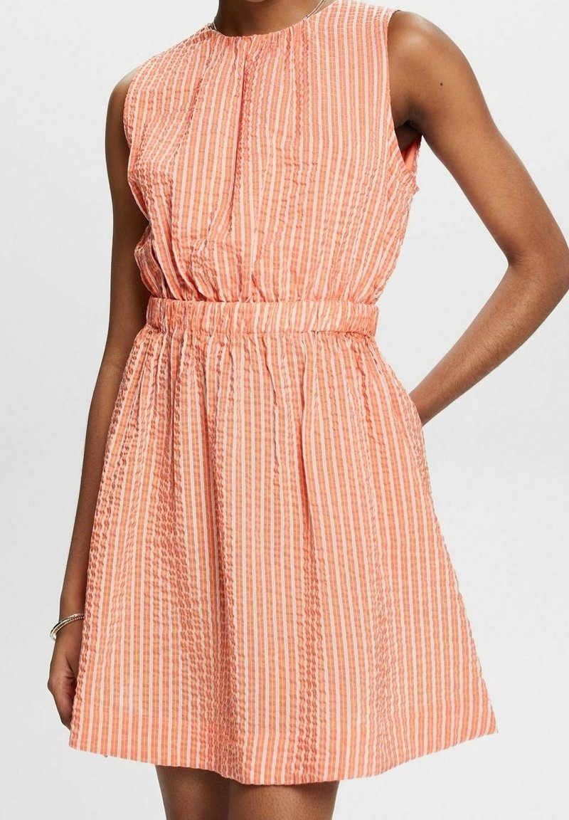 Robe sans manches à rayures pêche et blanches avec une taille froncée, présentant un col rond et un tissu texturé, tombant au-dessus du genou.