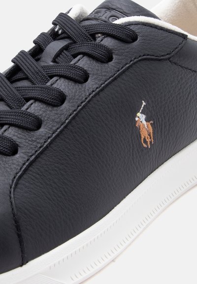 Μαύρο δερμάτινο αθλητικό παπούτσι με μαύρα κορδόνια και λευκή σόλα, διακοσμημένο με ένα μικρό κεντητό λογότυπο παίκτη πόλο στο πλάι.