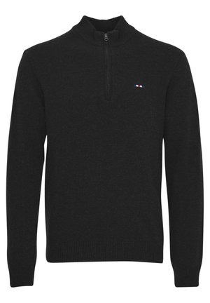 Juoda megztinis su užtrauktuku ir aukšta apykakle, raštuotais rankogaliais ir apačia, bei maža logotipas su raudonais, baltais ir mėlynais akcentais.