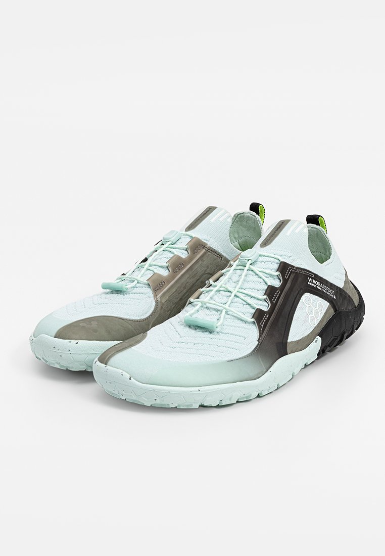 Zapatillas deportivas de color azul claro con una parte superior de malla texturizada, que cuentan con acentos grises, suela negra y tira de agarre verde. Diseño minimalista para mayor flexibilidad.