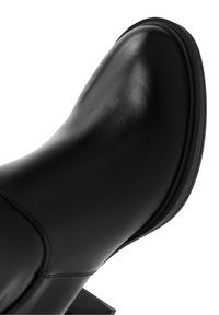 Bottine en cuir noir avec un bout rond, une texture lisse et un talon chunky. Présente des coutures minimales et une silhouette élégante.