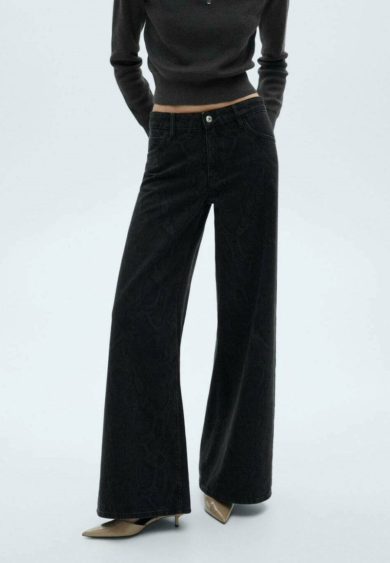 Svarta byxor med vida ben i en strukturerad ormskinnsmönstring, med en traditionell femfickorsdesign och metallknappstängning.