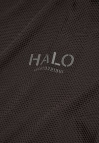 Strukturierter, dunkelbrauner Stoff mit einem Netzmuster, das ein bedrucktes Logo "HALO" und die Zahlen "196819721981" in Grau zeigt.