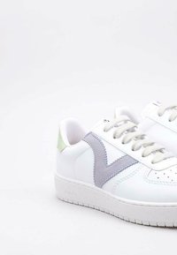 Baskets blanches avec des accents en gris et vert texturés, présentant un motif de swoosh contrastant, un bout rond et une semelle en caoutchouc texturé.