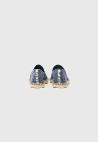 Espadrile din denim cu un material texturat de culoare albastră, vârful rotund și talpa de iută bej, stil espadrilă, cu un accent roz al logo-ului la călcâi.