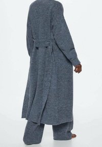 Długi, otwarty kardigan z dzianiny w ciemnoszarym kolorze z wiązaniem w talii, z długimi rękawami i luźnym krojem, zestawiony z pasującymi spodniami.