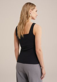 Must mustriba tank tops, laiemate rihmade ja ruudukujulise seljaga, ühes tükis heledate hallide laiade pükstega. Minimalistlik stiil, sile tekstuur.