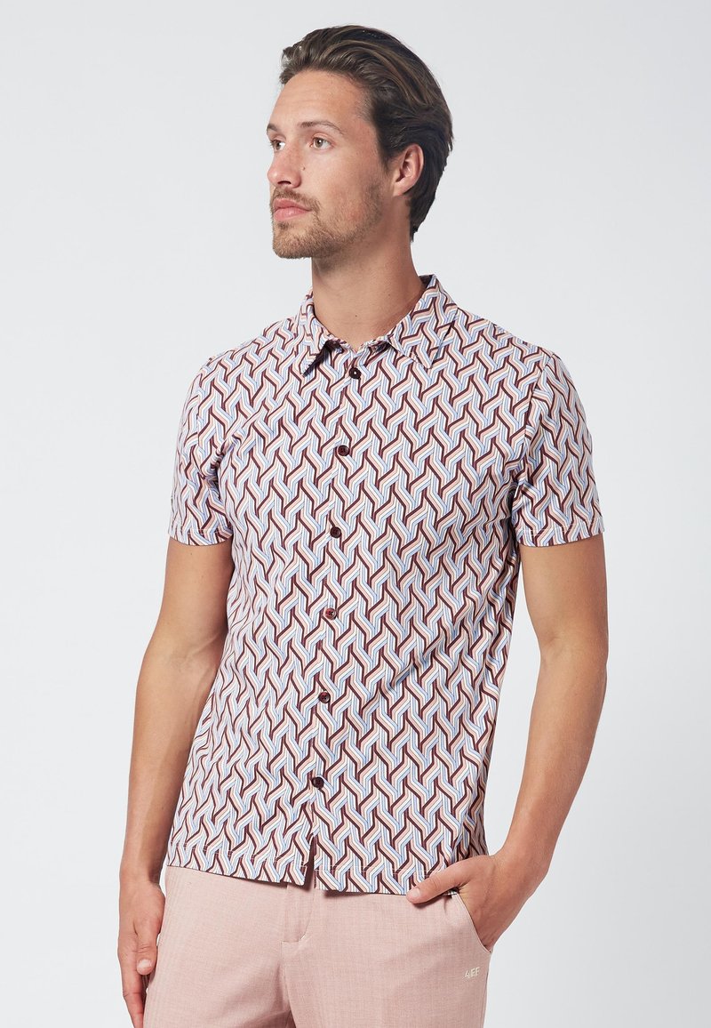 Camisa de manga corta con un patrón geométrico en rojo, azul y blanco. Diseño abotonado con cuello y tejido texturizado.