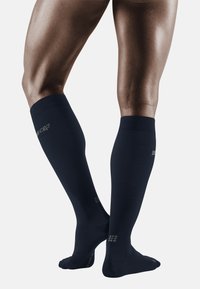 Marinefarbene knielange Kompressionssocken mit glatter Textur, verstärktem Zehenbereich und Logodetail an der Seite, entworfen für Unterstützung und Komfort.