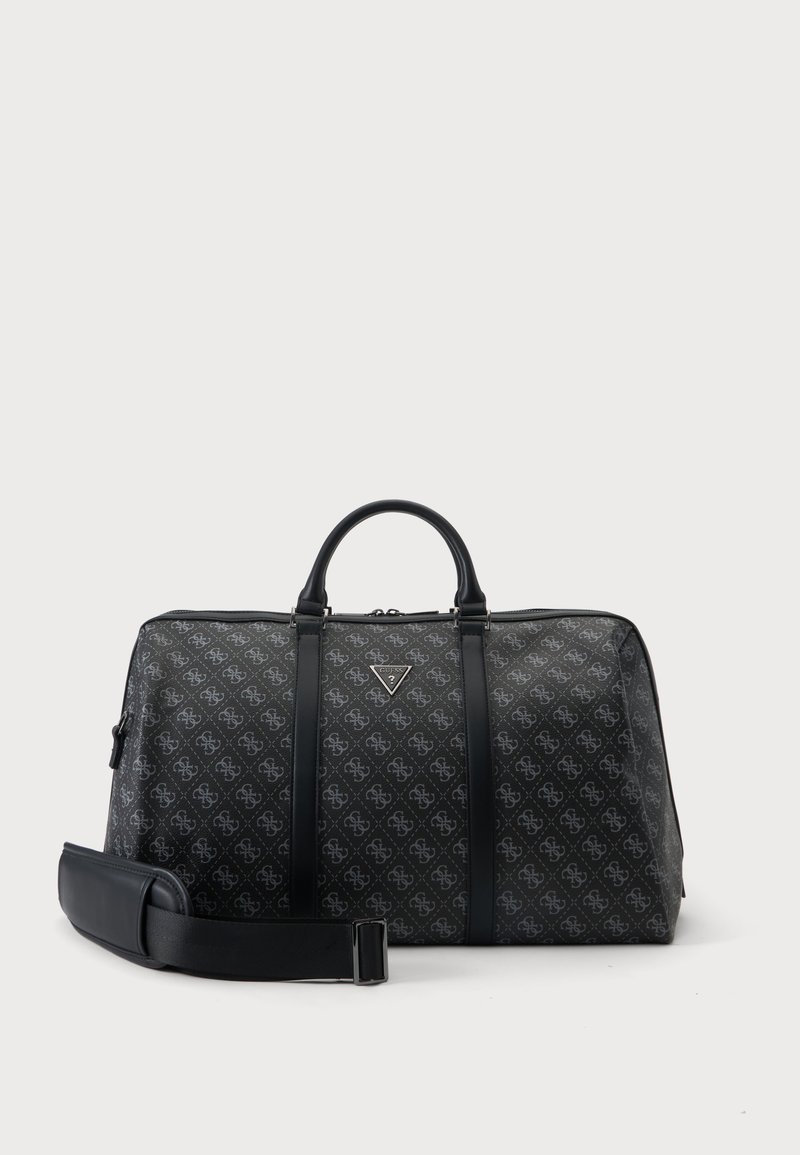 Sac polochon noir de créateur avec logo imprimé à motifs, doubles poignées et bandoulière amovible, présenté sur un fond clair uni.