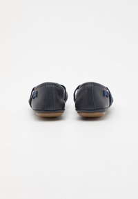 Pantofole in pelle blu con lati elastici, punta rotonda e una texture liscia. Presentano una suola in gomma marrone chiaro e dettagli di cucitura sottili.